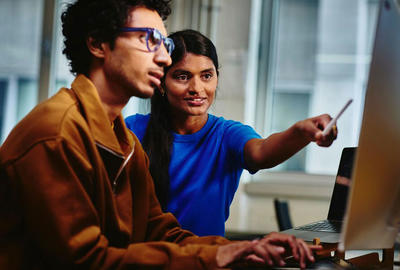 diverse coworker pointing to desktop screen