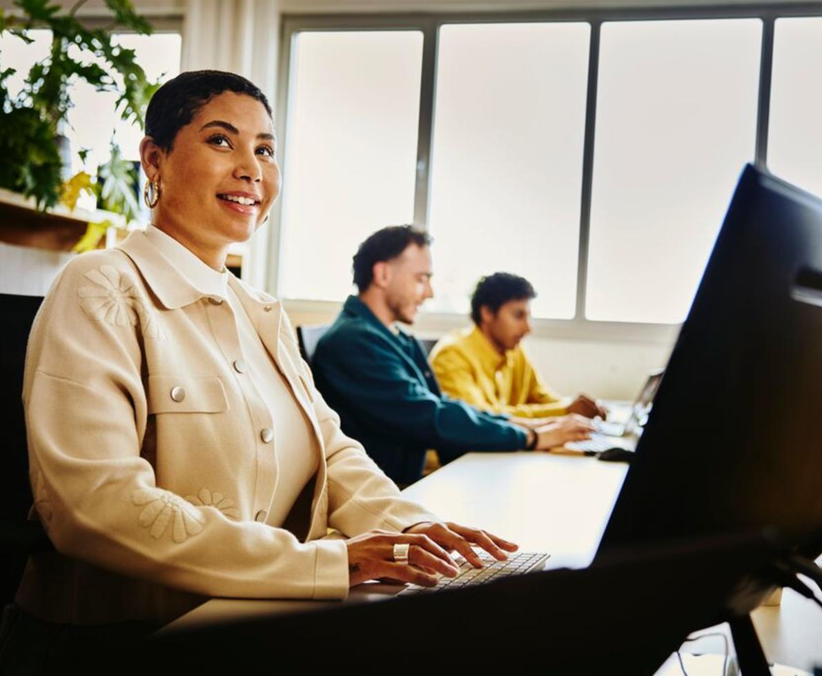 Woman working on her computer, sitting next to 2 other colleagues